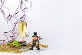 Two champagne glasses, one filled, lucky charm for New Year, white background, copy room