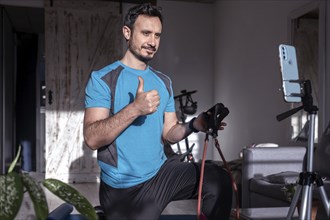 Attractive latin man personal trainer recording with phone content for online fitness business.