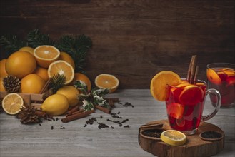 Wooden basket with oranges and lemons, two glass cups with punch, cloves and cinnamon sticks,