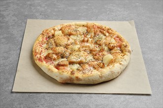 Pizza with chicken and pineapple on parchment paper