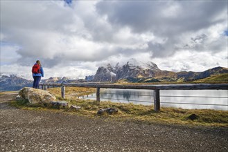 Hiker standing on stone, Sassopiatto, Sassolungo, Dolomites, Alpe di Siusi, lake, snow, clouds,