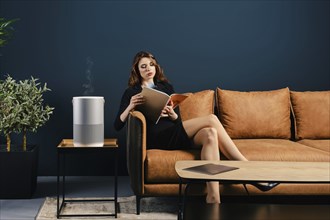 Confident young woman waiting for an appointment and reading magazine in waiting room