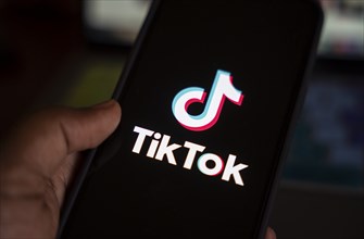 In this photo illustration, logo of Tiktok is displayed on mobile phone screen next to ban sign, in