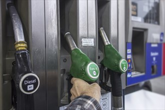 Man selecting petrol fuel pump nozzle at gas station for refueling his car in Europe