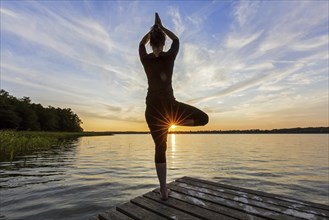 Woman practicing standing posture Vrikshasana, Tree Pose, one legged balancing asana of the