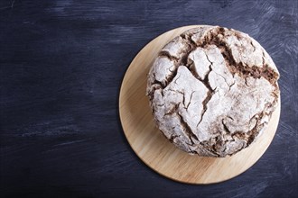 Yeast free homemade bread with whole rye and wheat grains on black wooden background. Top view,