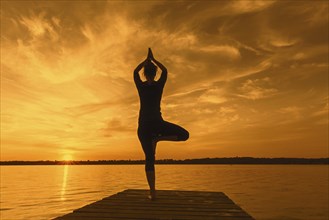 Woman practicing standing posture Vrikshasana, Tree Pose, one legged balancing asana of the