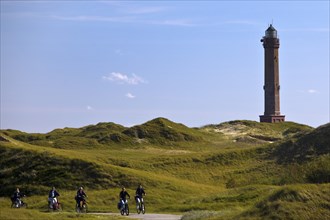 Large Norderney lighthouse in the dune landscape with cyclists, Norderney Island, East Frisia,