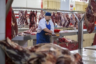 Man chopping meat and bones, butcher's shop with fresh meat, market at Osh bazaar, Bishkek,