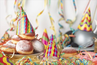 Scene with doughnuts, streamers and colourful party hats on a table