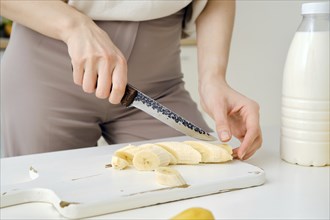 Closeup view of female hands cutting banana on kitchen table