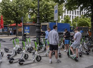 Young people surrounded by parked electric scooters, Unter den Linden, Berlin, Germany, Europe