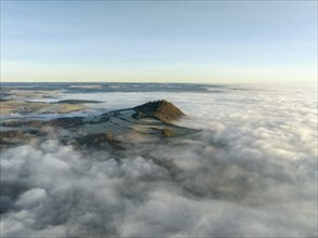 Aerial view of the wintry and fog-covered Hegaulandschaft shortly after sunrise, the volcanic cone