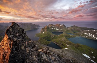 View over mountain top and sea, dramatic sunset, at the summit Hermannsdalstinden, with lakes