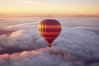 Colorful hot air balloon floats over a sea of clouds at sunset at sunset with orange and blue skies