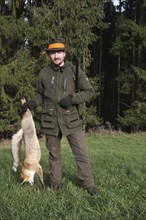 Hunter with a red fox (Vulpes vulpes) shot during a hunt for brown hares (Lepus europaeus) Lower