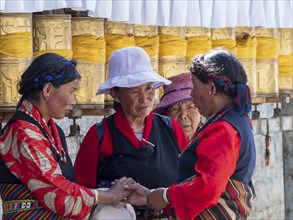 Pilgrims at golden prayer wheels, Tibetan woman in conversation, Xigaze, Tibet, China, Asia