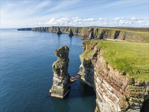 Aerial view of the rugged coastal landscape at Duncansby Head with rock tower, behind it the