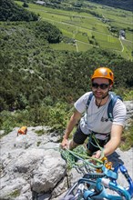 A mountaineer with helmet and safety equipment climbing on a rock face, alpine climbing with rope,