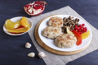 Meatballs with rice mushrooms, sweet peppers and pomegranate seeds on black wooden background.