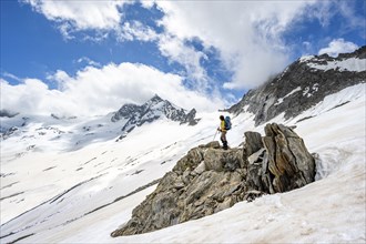 Mountaineer on a rock between snow, descent from the summit of Schönbichler Horn, view of