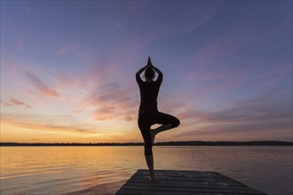 Woman practicing standing posture Vrikshasana, Tree Pose, one legged balancing asana of the