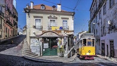 A yellow tram on a cobblestone street passing by a vintage building under a clear blue sky, Alfama,