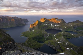 View over mountain peaks and sea, dramatic sunset, from Hermannsdalstinden, with lakes