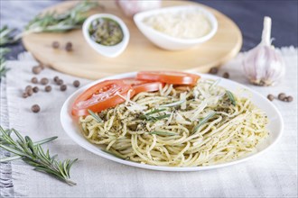 Spaghetti pasta with pesto sauce, tomatoes and cheese on a linen tablecloth. close up, selective