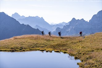 Four hikers on the Carnic High Trail, small mountain lake, Carnic Main Ridge, Carnic Alps,