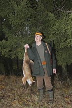 Hunter with a red fox (Vulpes vulpes) shot during a hunt for brown hares (Lepus europaeus) Lower