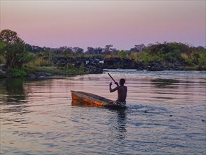 A Kavango fisherman pulls a net through a side arm of the Okavango River in the evening with his