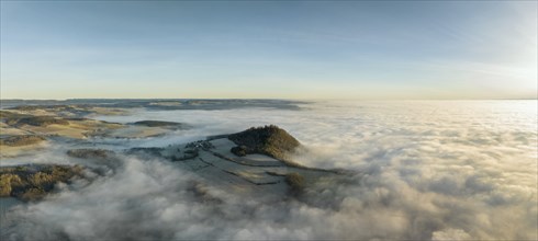 Aerial panorama of the wintry and fog-covered Hegaulandschaft shortly after sunrise, the volcanic