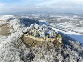 Aerial view of the snow-covered Hegau volcano MÃ¤gdeberg, with remains of a castle wall, surrounded