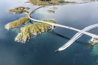 Aerial view of bridge connecting islands at the norwegian coast, motor boat passing below the