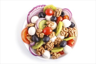 Salad with cherry tomatoes, mozzarella cheese, black olives, kiwi, and walnuts isolated on white