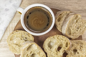 Sliced bread and a cup of coffee on a wooden board and linen tablecloth