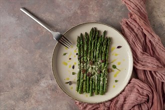 Grilled asparagus, spices and herbs, parmesan cheese, on a beige plate, top view, rustic, no people