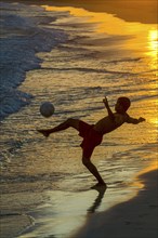 Young men playing football at sandbeach in twilight. Santa Maria. Sal. Cabo Verde. Africa