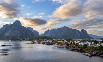 Village view of the fishing village Reine, traditional red Rorbuer cabins, at sunset, in the back