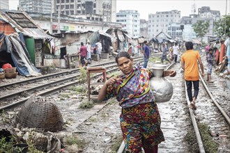 Woman carrying water on the railway tracks, Tejgaon Slum Area, Dhaka, Bangladesh, Asia