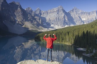 Tourist with open arms on look-out point looking over Moraine Lake in the Valley of the Ten Peaks,