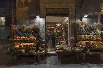 Customers in a fruit shop open at night in the historic centre, Genoa, Italy, Europe