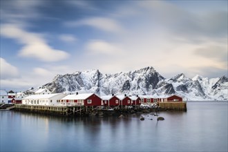 Rorbuer cabins of Hamnoy by the fjord, snowy mountains in the back, Hamnoy, Reine, Moskenesoya,