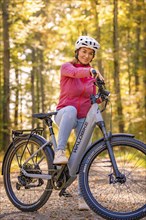 Woman sitting on Ebike through autumn forest, Black Forest, Gechingen, Germany, Europe