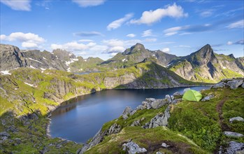 Green camping tent, mountain landscape with lake Tennesvatnet, at sunrise, behind peak of