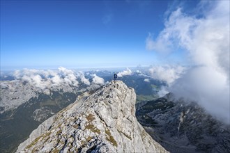 Mountaineer on a rocky narrow mountain path with mountain panorama, mountain tour to the summit of