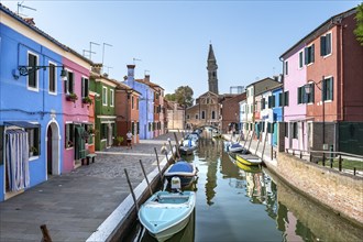 Colourful houses on the canal, canal with boats and colourful house facades, behind the church