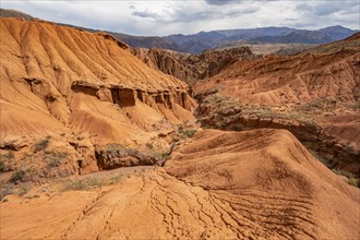 Eroded mountain landscape with sandstone cliffs, canyon with red and orange rock formations,