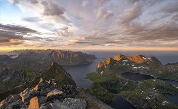 View over mountain peaks and sea, dramatic sunset, mountaineers at Hermannsdalstinden, with lakes